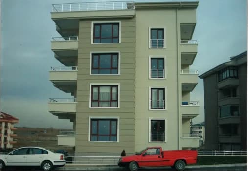 Tamamlanmış dört katlı krem cepheli apartman binasının caddeden fotoğrafı